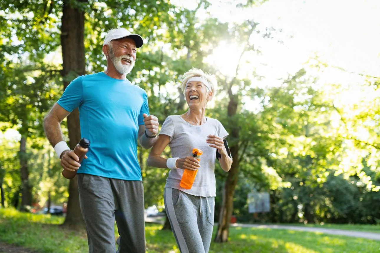 An older couple jogging outdoors, staying active and healthy together